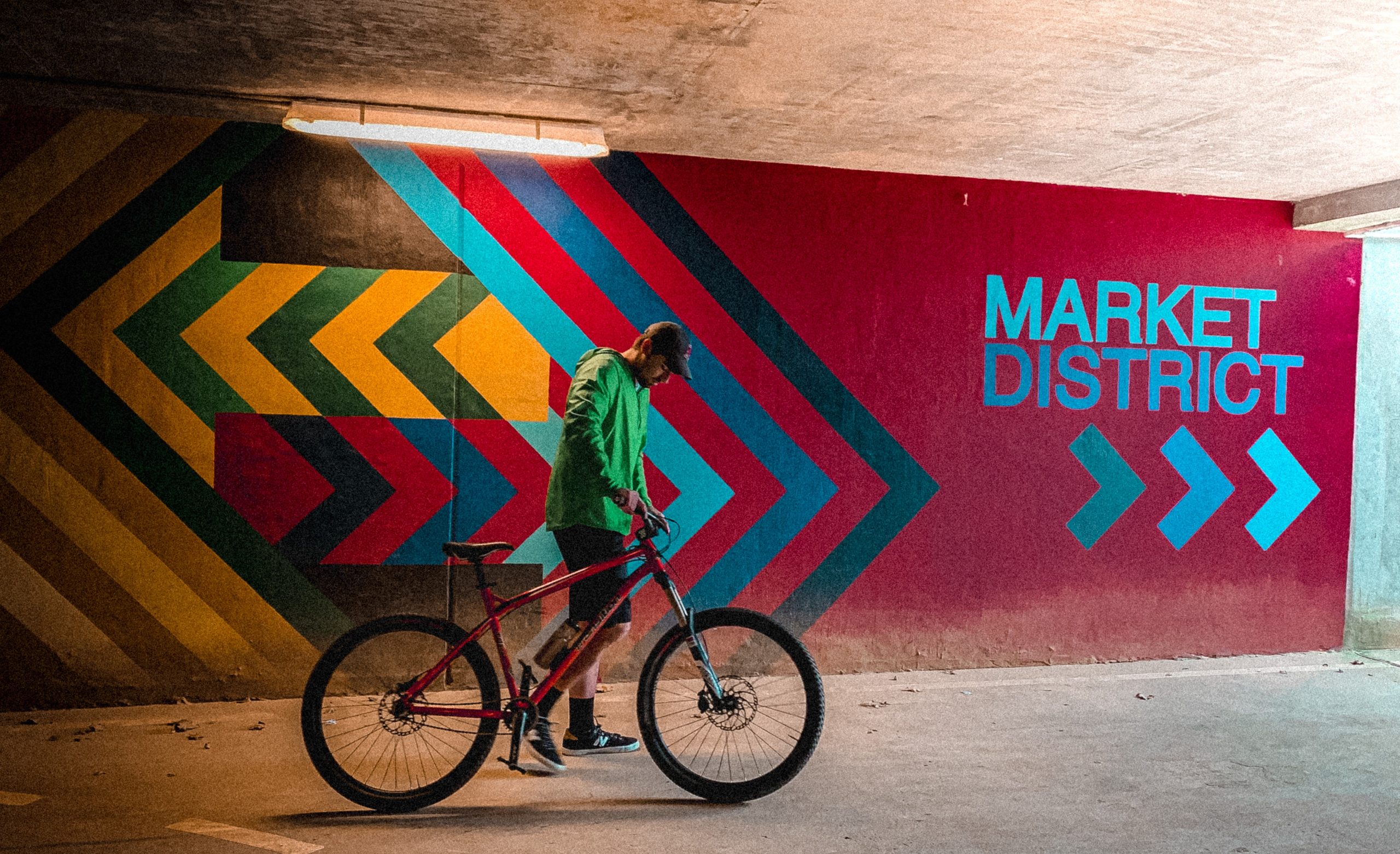 Cyclist with bike in a tunnel with colorful wayfinding artwork in the background